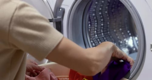 Woman Loading Colorful Clothing into Washing Machine
