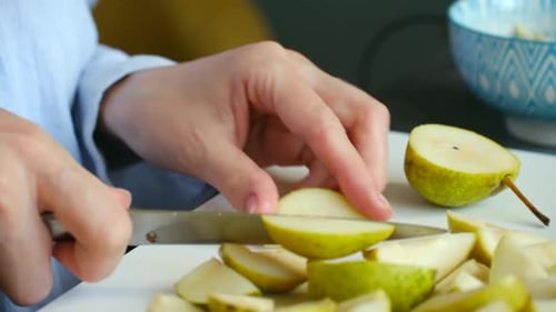 Woman's Hands Slicing Fresh Green Pear on a Cutting Board