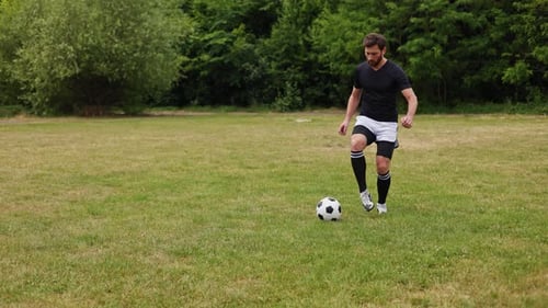 Lively Man Races Across Sprawling Grassy Field Adeptly Guiding Soccer Ball