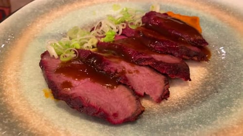 Tasty steak cut in thin slices with spring onion and glazed sauce, food on a plate, 4K shot
