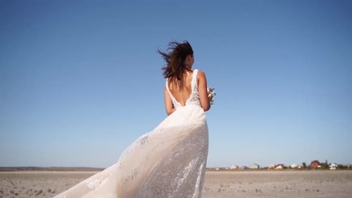Pretty Woman in Gorgeous Wedding Dress Walking at Desert Landscape Windy Weather Elegance Bride with