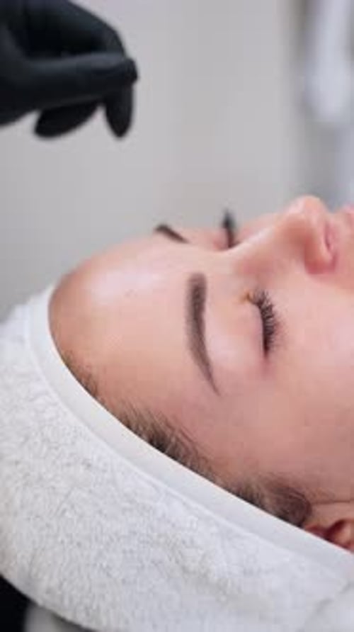 Woman Receiving Eyebrow Treatment in Treatment Room