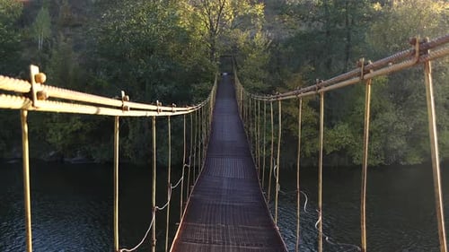 Camina por el puente de hierro que cuelga sobre el río. El puente colgante de hierro se tambalea.