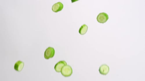 Cucumber Slices Falling on a White Background