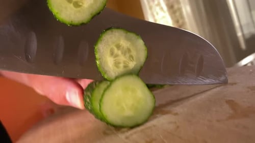 Slicing Fresh Cucumber on Wooden Cutting Board