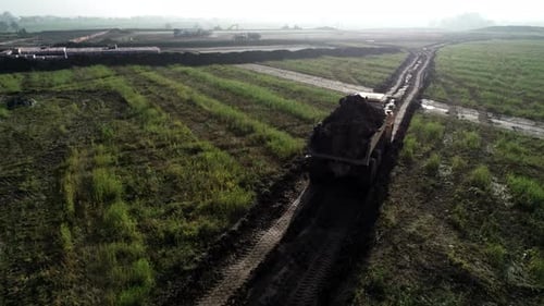 Aerial following dump truck on a construction site of a big logistic center in the ground leveling s