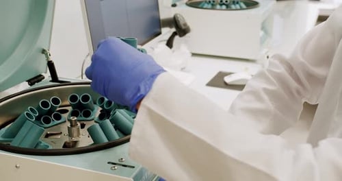 Scientist Places Test Tubes into Centrifuge