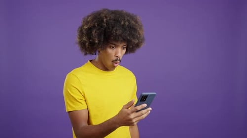 Young Adult Shocked by Phone Against Purple Backdrop