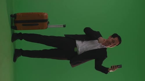 Businessman With Luggage Smiling And Taking Photo On Smartphone While Standing In The Green Screen