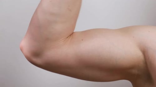 The Muscular Arm of the Athlete Squeezes and Shows the Biceps Physical Strength