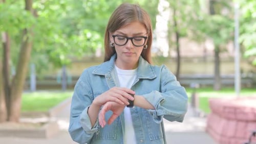 Woman Checking Time on Smartwatch in Park