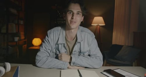 Young Man Talking At Desk Indoors At Night