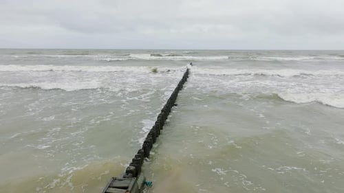 Establishing aerial view of Baltic sea coast on a overcast day, old wooden pier, white sand beach, l