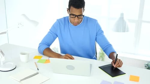 Young Adult Working on Computer with Tablet
