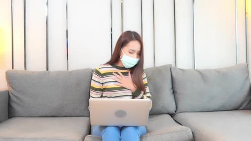 Woman in Mask Using Laptop and Coughing