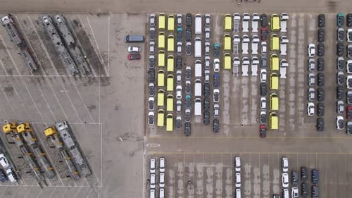 An aerial perspective showcasing a large parking lot with rows of vehicles, including cars, yellow v