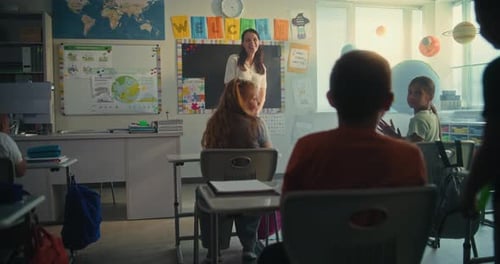 Female Teacher Introducing New Young Student in Front of Class Full of Elementary School Children