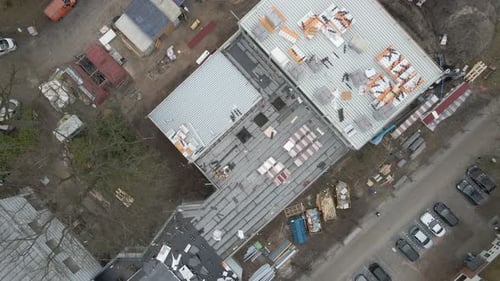 Vista aérea de arriba hacia abajo de un trabajador de la construcción que trabaja en una gran obra de construcción: Zumbido levantándose y