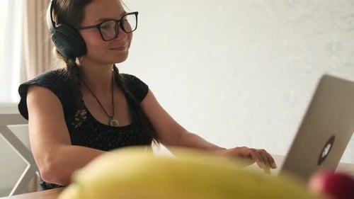Woman with Headphones Working on Laptop at Home