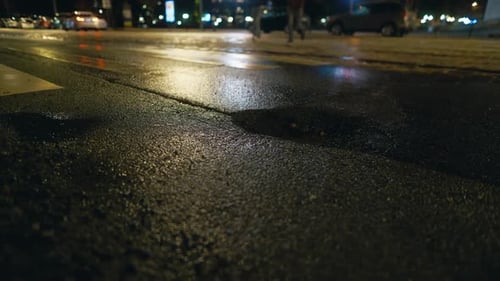 Imagem desfocada da rua da cidade à noite com poça de água na superfície da estrada de asfalto