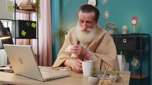 Sick Ill Senior Man Suffering From Cold Flu Allergy Blows Sneezes Wipes Snot Works on Laptop at Home