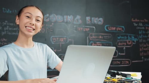Süßes asiatisches Mädchen-Programmiersystem mit Laptop an der Tafel. Erbauung