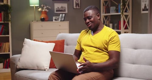 Man Using Laptop on Couch for Video Call