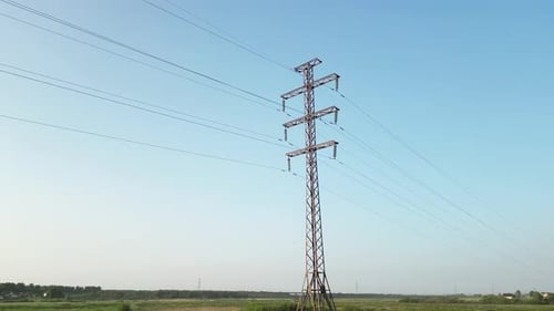 Metal Electricity Pylon Standing in a Field Carrying Power Lines Across the Countryside on a Sunny