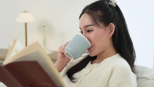 Woman Enjoying Reading Book Indoors With Drink