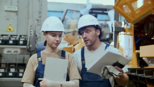 Maintenance Technician Discussing Machinery with Female Colleague in Factory