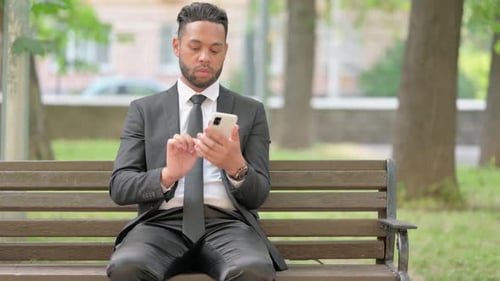 Man in Suit Uses Cell Phone on Bench