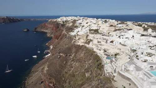 Aerial shot of a whitewashed city on a mountain by the sea against the sky