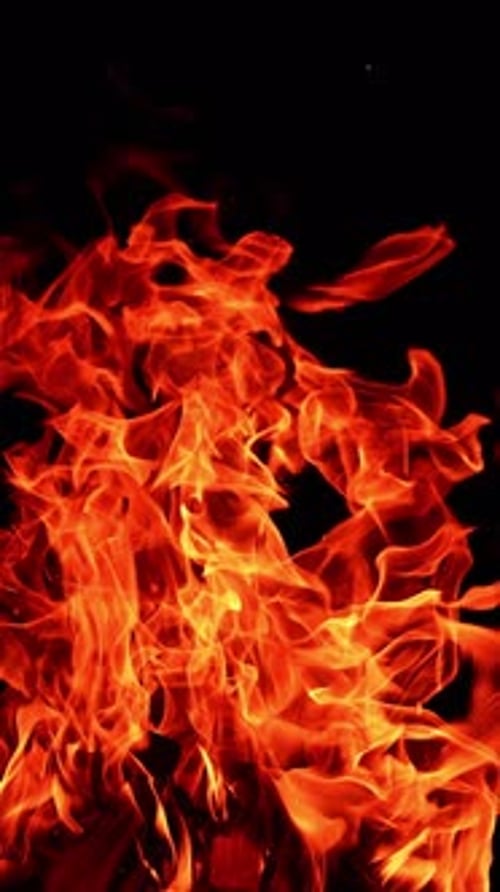 Fire flame on isolated black background. Fire sparks glowing with warm. Vertical video