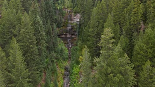 Waterfall, water falling down rocky mountain in forest.