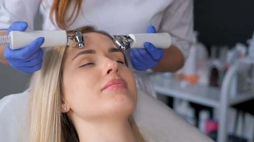 The Cosmetologist Performs the Procedure of Microcurrent Treatment of the Facial Skin Massage