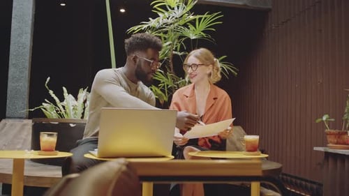 Colleagues Working on Project in Modern Cafe