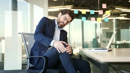 Man Rubbing Knee Due to Pain in Office