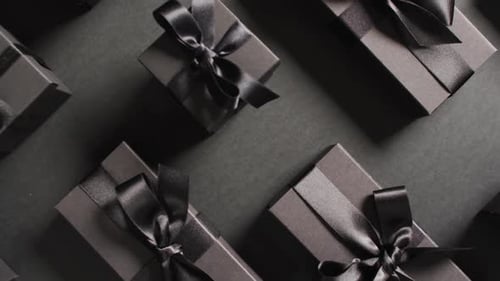Overhead view of black gift boxes tied with black ribbons on black background