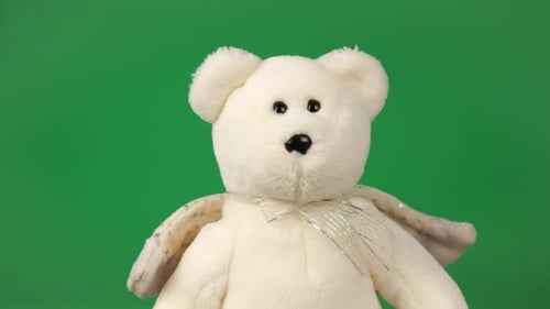 Stuffed and fluffy teddy bear toys with angel wings playing and dancing on a green background.