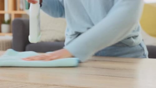 Woman wiping a table at home. Closeup of a female sanitizing and spring cleaning a table surface