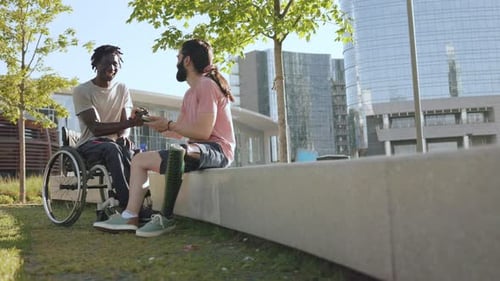 Multiracial people with physical disabilities greeting each other outdoor at park city
