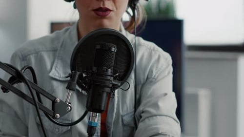 Internet Live Radio Talk Show Host with Headphones Talking to Audience at Microphone in Studio