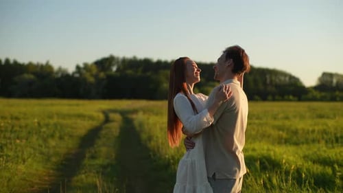 Portrait of Loving Young Man and Redhead Woman in Love Hugging Kissing Stroking Standing on Field