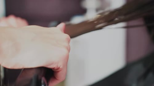 Hair Stylist Straightening Hair in a Salon