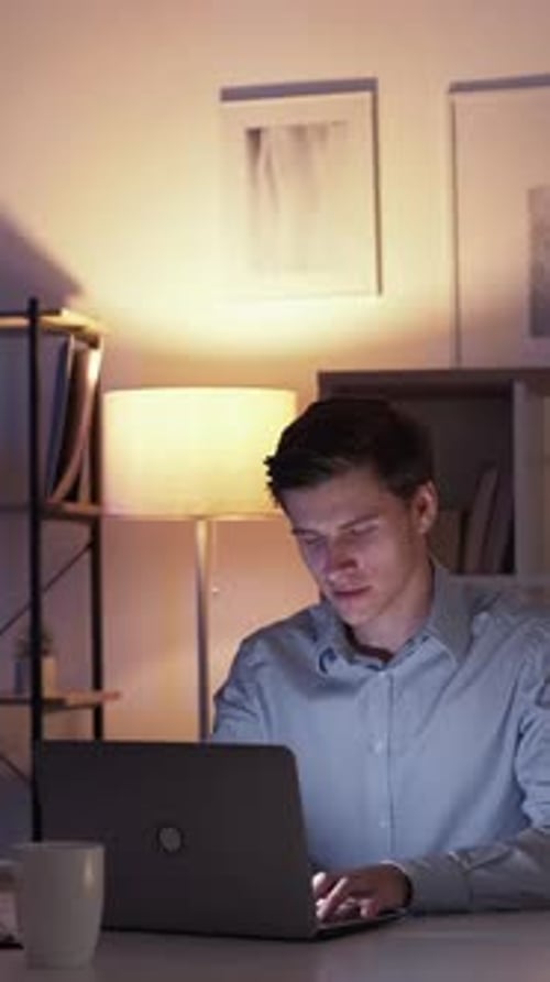 Man Works on Laptop Late at Night at Home