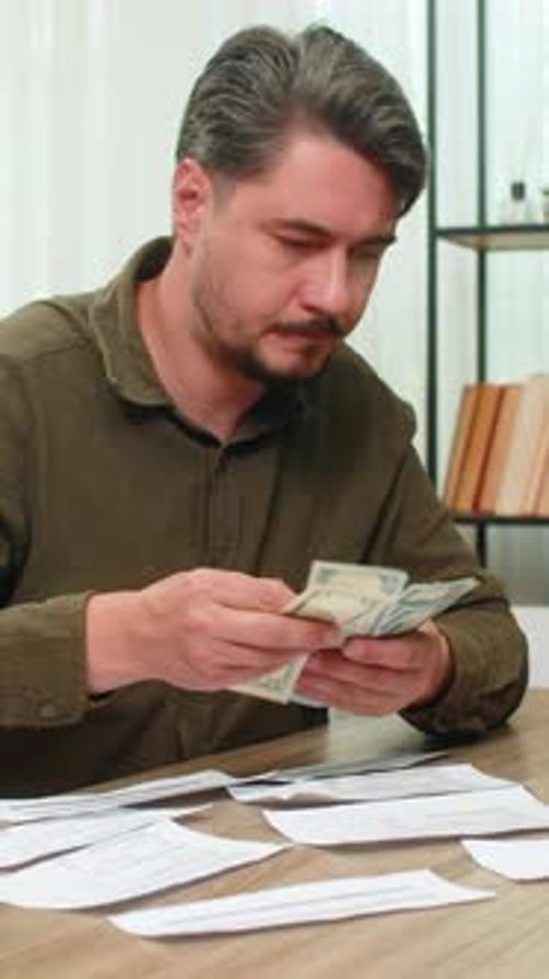 Man Counting Cash at Desk with Bills