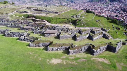 Aerial descend above terraced stone walls and grass lawns overlooking Cusco Peru