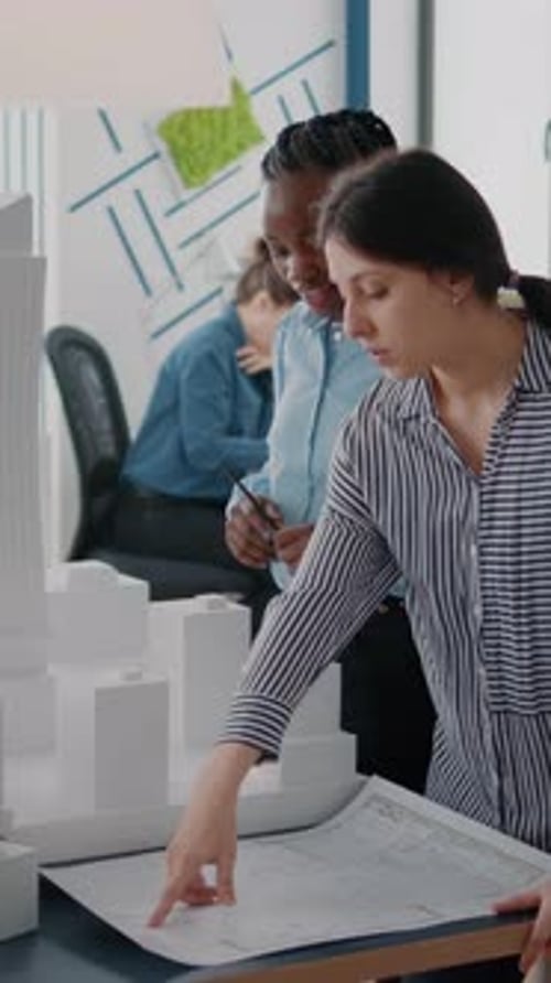Vertical Video Multi Ethnic Women Analyzing Bulding Model and Blueprints Plan to Develop