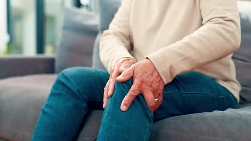 Adult Holding Knee in Pain on Couch