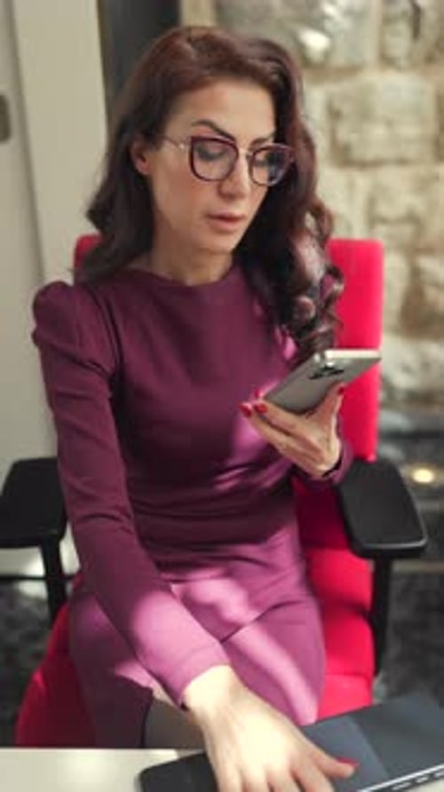 A Professional Woman Engaged in a Phone Call While Sitting at Her Stylish Office Desk